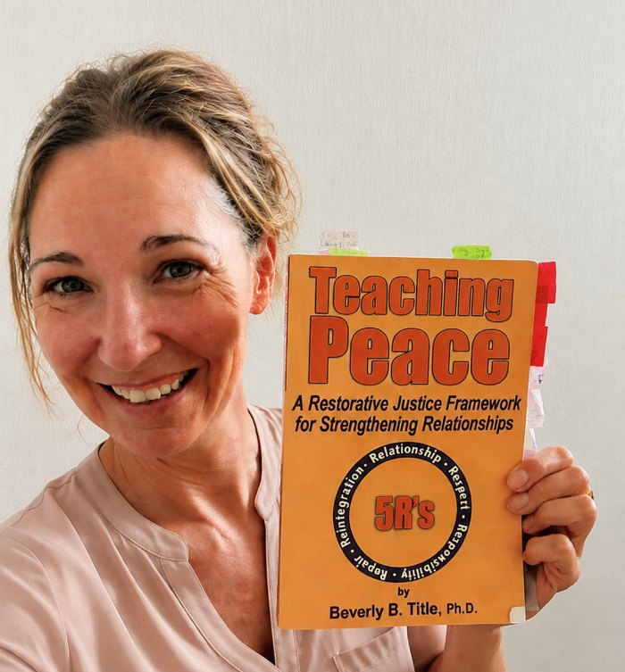 Summer B. Joy holding Teaching Peace by Dr. Beverly B. Title, tabbed and annotated